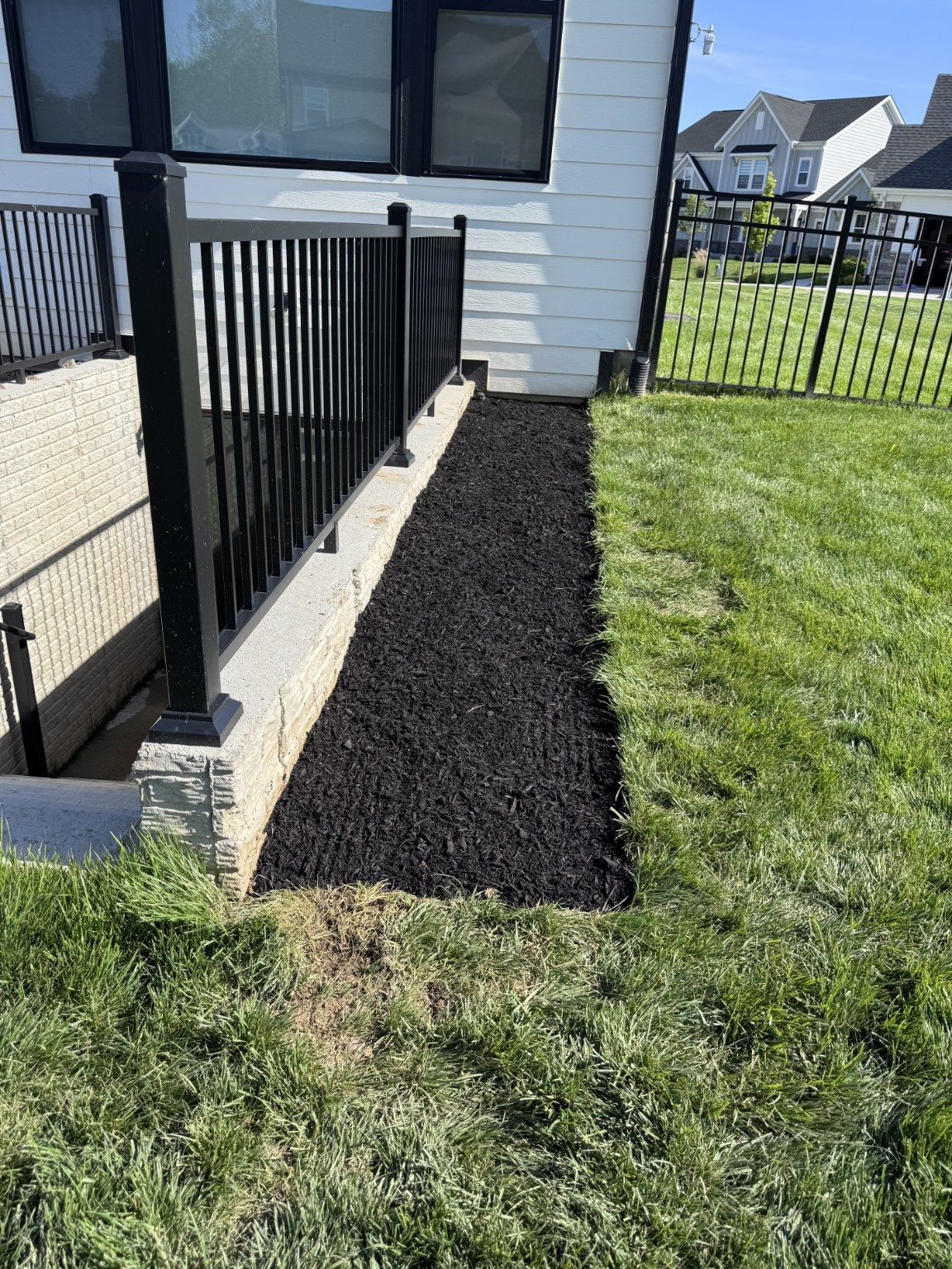 A neatly mulched strip beside the black railing.
